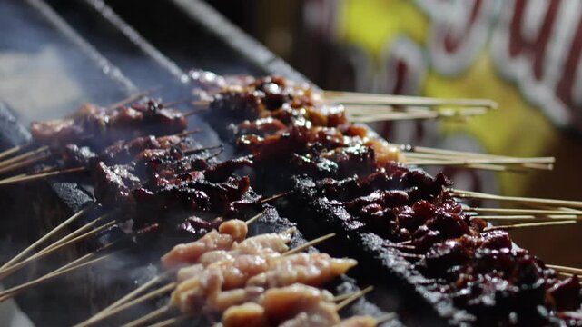 Satay seller tending his satay stall and making sure the satay is properly grilled. Satay is seasoned meat or chicken skewered with bamboo stick.