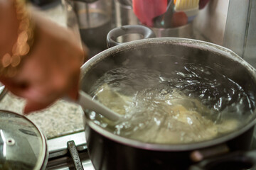Chef cooking ravioli in boiling water with ladle