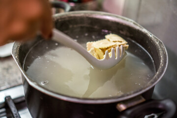 Chef using skimmer to check ravioli in boiling water
