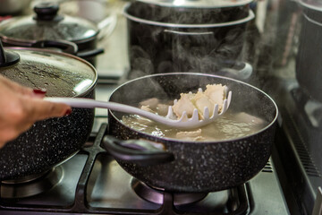 Chef preparing ravioli in boiling water with red meat sauce for lunch