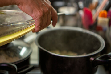 Chef pouring olive oil into pot with meat sauce for ravioli