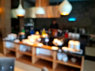 A blurry, out-of-focus photo of a buffet table in a hotel restaurant, showing bowls, plates, coffee, desserts, breakfast items, and beverages. As a background photo, the viewpoint is at eye level.