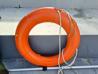 A Bright Orange Lifebuoy Hanging on a Stone Wall for Safety	