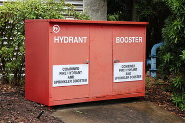 Red metal Hydrant Booster cabinet surrounded by garden plants