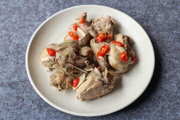 Steamed chicken served in a plate with various herbs and spices	