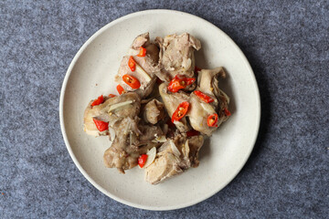 Steamed chicken served in a plate with various herbs and spices	