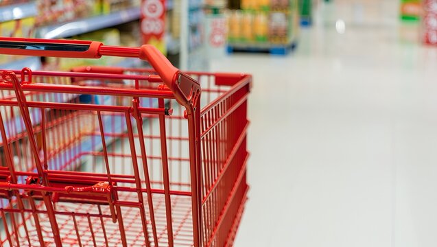 Bright red shopping cart navigates an aisle, ready for retail shopping and consumer activity.