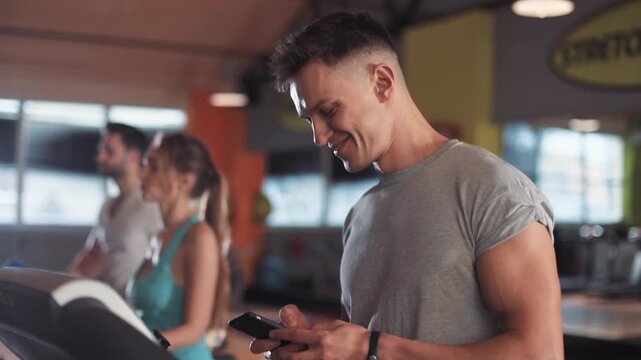 Close up face man use phone on a treadmill in gym sportsman sport fitness internet face technology fit male smile workout athlete sportswear networking body exercise healthy mobile smartphone young