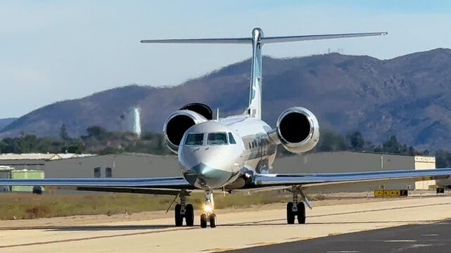 Taxiing silvery corporate jet in midday light