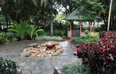 Paved area with a water feature, gazebo and tropical plants at the Palmetum in Townsville,...