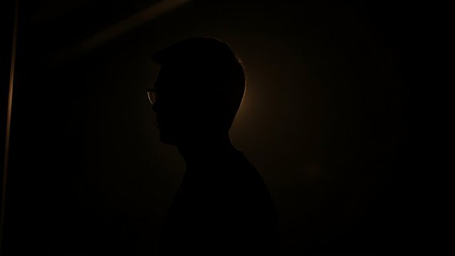 A solitary figure in a softly lit room, lost in thought with a gentle glow highlighting their silhouette.