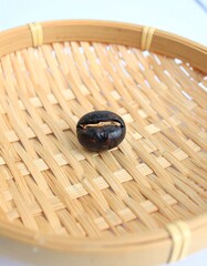 Single dark seed in a woven, light-colored, shallow basket