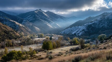 Fototapeta premium Sunlit valley nestled in snow-dusted mountains