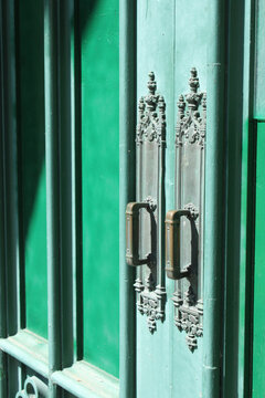 Poign&eacute;es de porte anciennes en m&eacute;tal sur porte verte vintage &eacute;clair&eacute;e par la lumi&egrave;re naturelle