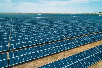 Large solar energy farm with numerous solar panels capturing sunlight in a wide open space during...