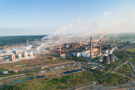 Air pollution from industrial facilities causes environmental concerns in urban areas during sunset hours.