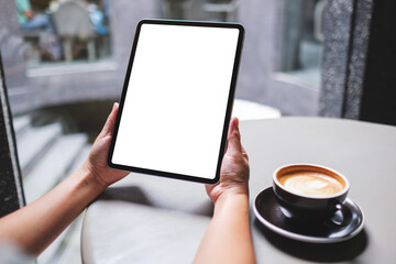 Mockup image of a woman holding digital tablet with blank white desktop screen in cafe