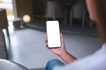 Mockup image of a woman holding and using mobile phone with blank desktop screen in cafe