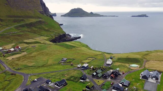 Drone Pullback Reversing Over Gasadalur Village and Sea Cliffs, Faroe Islands