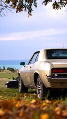 Classic car parked overlooking ocean, autumn leaves