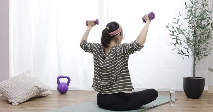 Woman from the back, lifting dumbbells, symbolizing fitness and a commitment to a healthy lifestyle for overall wellness, a healthy and fit lifestyle. Good habits for a balanced life