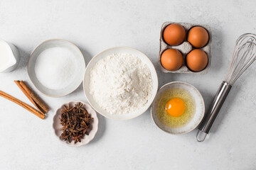 Baking ingredients flat lay with flour, eggs, sugar, and spices on marble surface