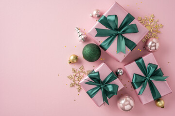 Festive pink wrapped gifts decorated with green ribbon and ornaments on pastel background