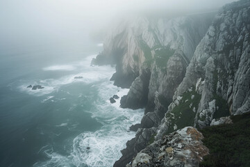 Fototapeta premium Sea cliffs in fog with ocean waves, dramatic coastal landscape