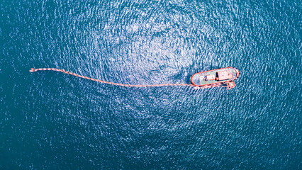 Boom floating barrier used to contain an oil spill. An offshore vessel performing oil spill...