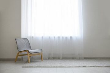 Chair and carpet near light curtain in room