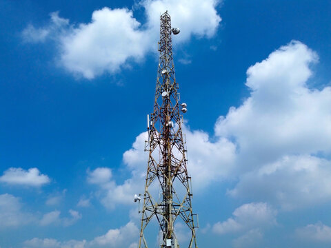 Cell tower with antennas against blue sky and clouds, representing 4G 5G mobile network, internet, and modern telecommunication technology. - Powered by Adobe