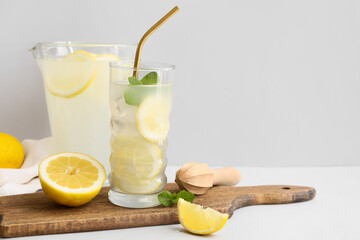 Glass and jug of fresh lemonade with mint on grey background