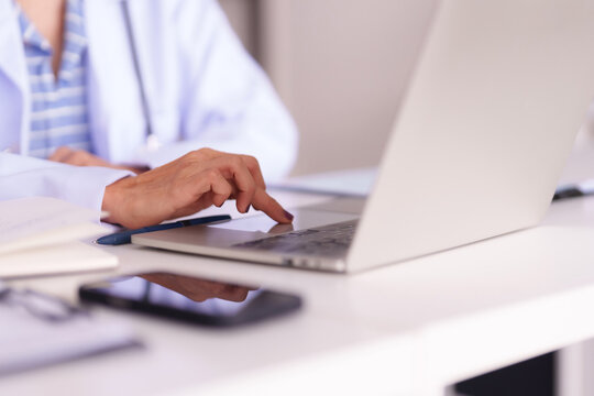 Female doctor healthcare professional using laptop computer in medical office for patient data management digital health solutions