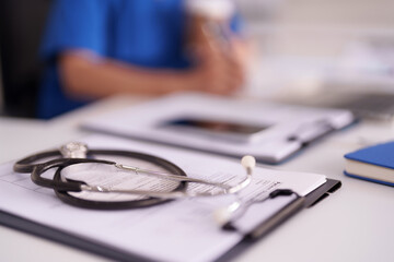 Professional adult female doctor in a medical office focused on patient care with stethoscope and paperwork