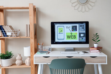 Web designer's workplace with computer monitor near beige wall in office