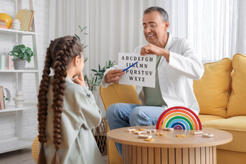 Male speech therapist working with little girl in office
