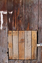 Weathered rustic wooden door with mismatched repair planks and metal bolts