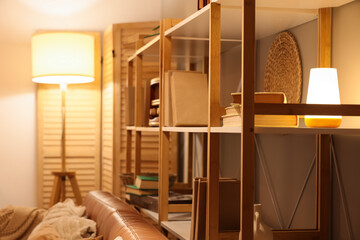 Wooden shelf unit with books and glowing lamp in living room