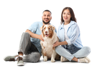 Young couple with Australian Shepherd dog sitting on white background
