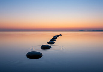 Serene landscape of smooth stones in calm water at sunset, symbolizing a tranquil path forward.

