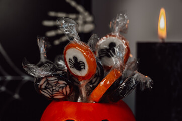 closeup of pumpkin bowl with candies , treat near black candles and other decorations