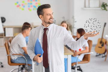 Male Science teacher with clipboard and molecular model in school office