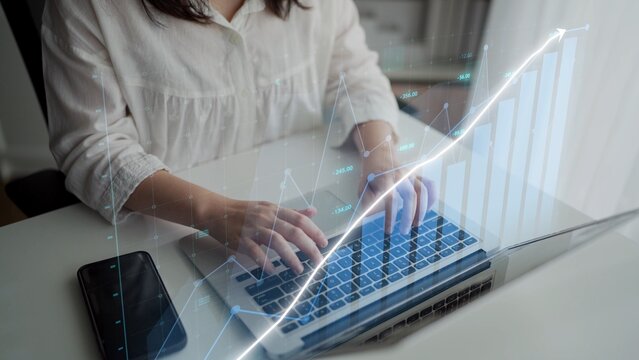 A business professional engages in financial analysis using a laptop in a modern office setting, with data visualization graphs illustrating growth and trends. Copula - Powered by Adobe