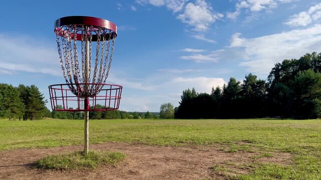 Sport equipment focus: disc golf basket in scenic countryside park landscape in Tukums
