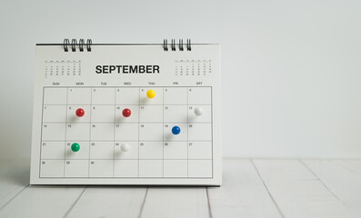 Desk calendar for september with colorful push pins on white background, planning, scheduling and...