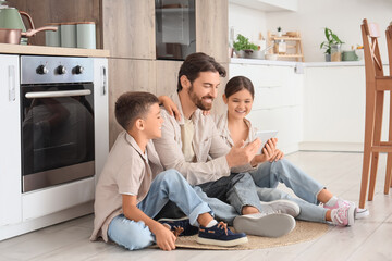 Happy father with his children using tablet computer in kitchen
