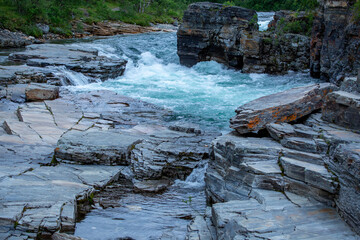 The turquoise water of the beautiful Abisko River, Abiskojokk, flowing between the rocks at Abisko...