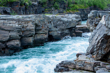 The turquoise water of the beautiful Abisko River, Abiskojokk, flowing between the rocks at Abisko Canyon, Sweden, Northern Europe