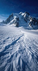 Snowy mountain landscape with textured ice.  Vast glacier, with intricate patterns in the snow, stretches towards a majestic, snow-capped peak under a vibrant blue sky