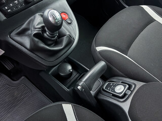 This is an interior view of a car that features a traditional manual gear stick, a handbrake, and a...
